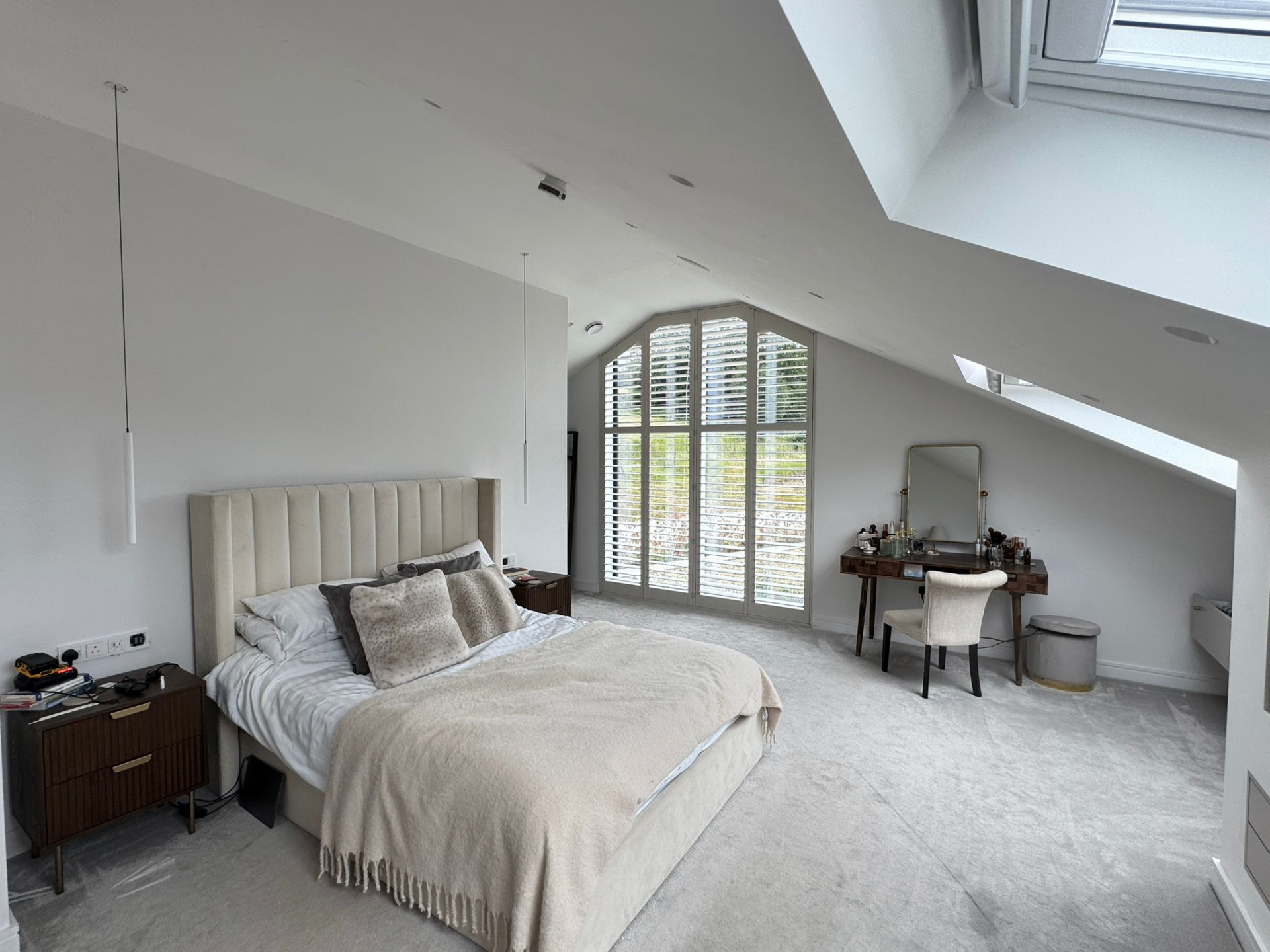 Full room view of a bedroom with shaped shutters fitted to a gable-end feature window