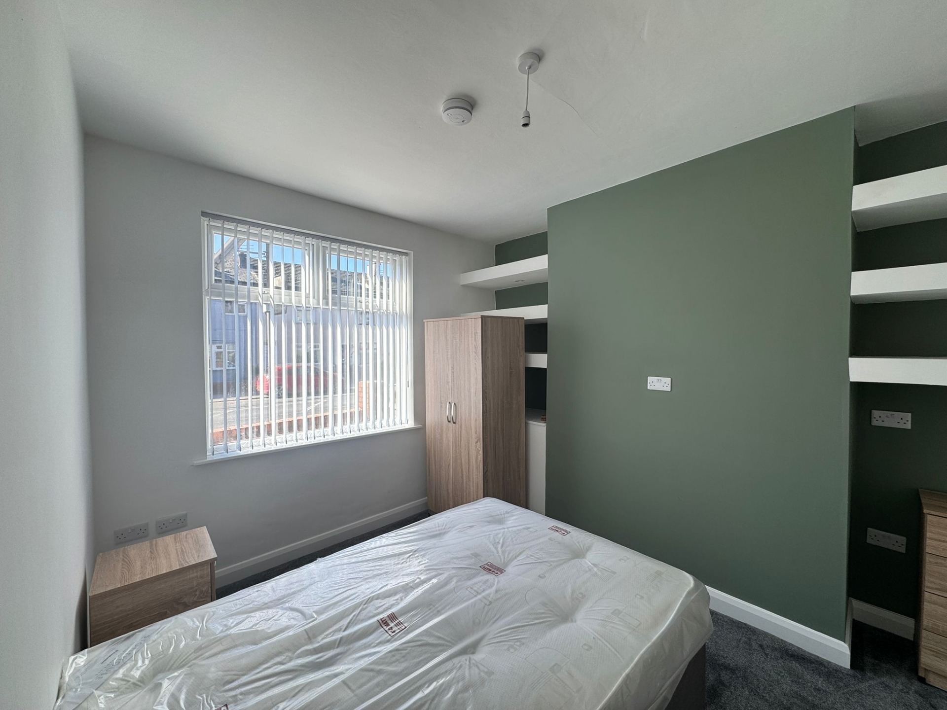 White vertical blinds fitted to a bedroom window with alcove shelving