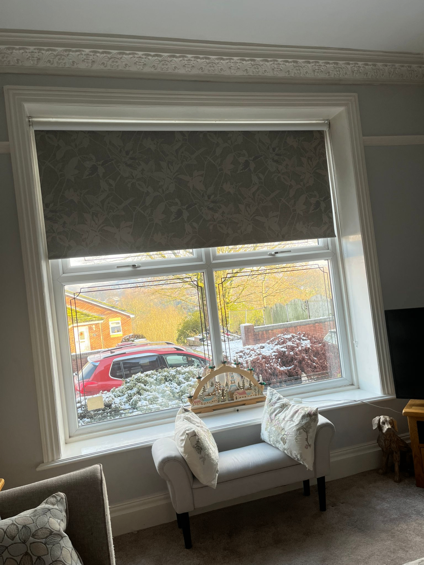 Patterned taupe roller blind fitted in a period living room bay window