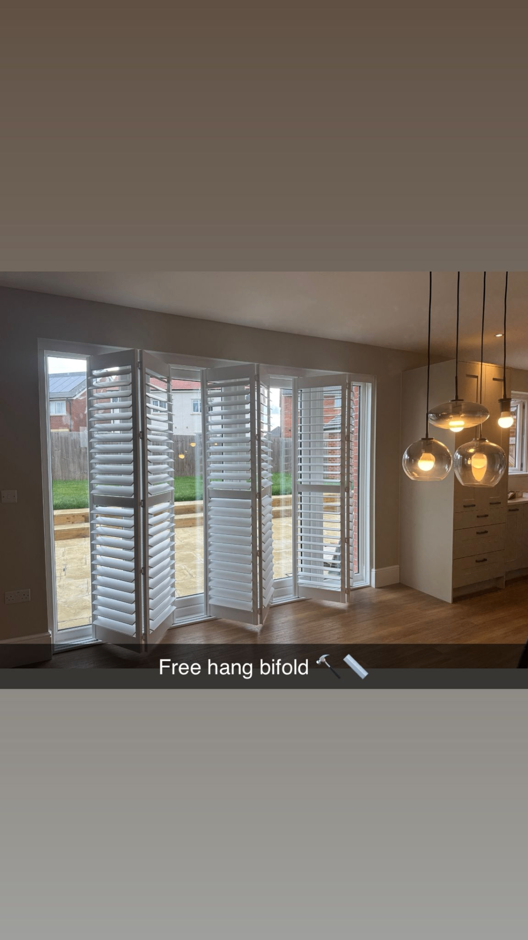 White free-hang bifold shutters partially folded across patio doors in a modern dining area